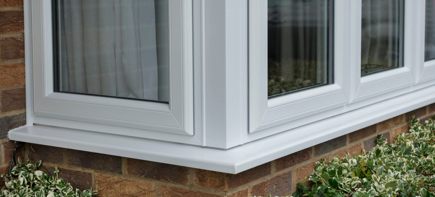 A white uPVC casement bay window fitted to a brick house, close-up exterior view