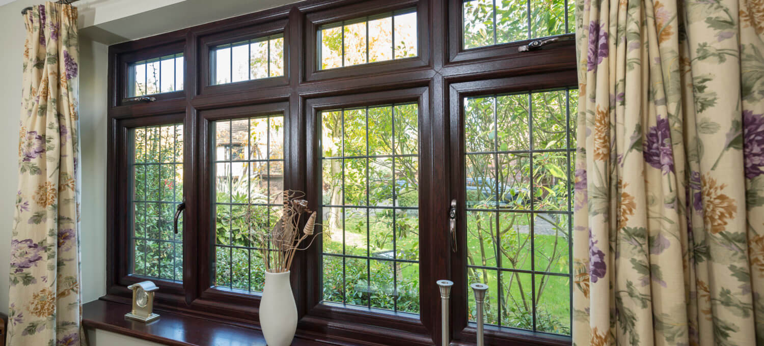 Interior view of a rosewood woodgrain uPVC flush sash window looking out onto a garden