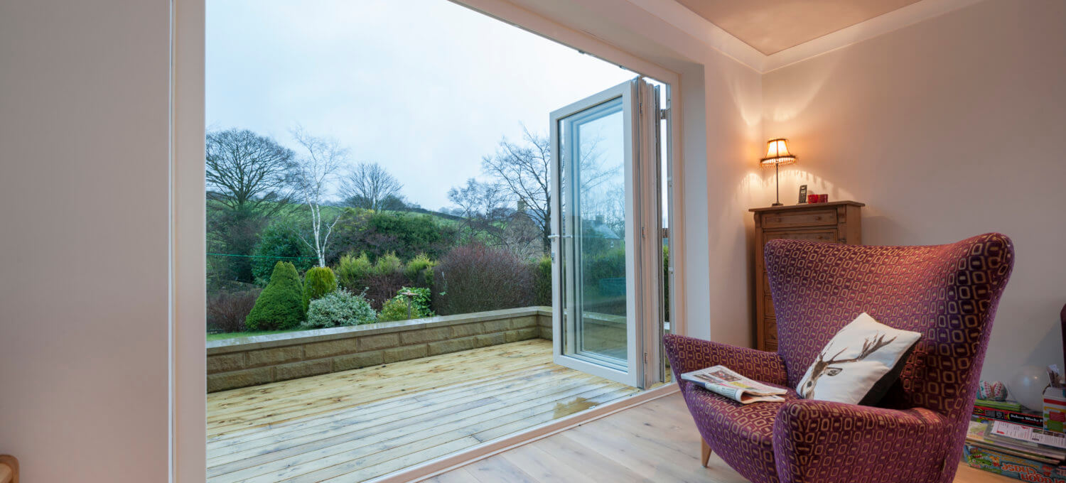 A white uPVC Deceuninck entrance door opening onto a garden deck