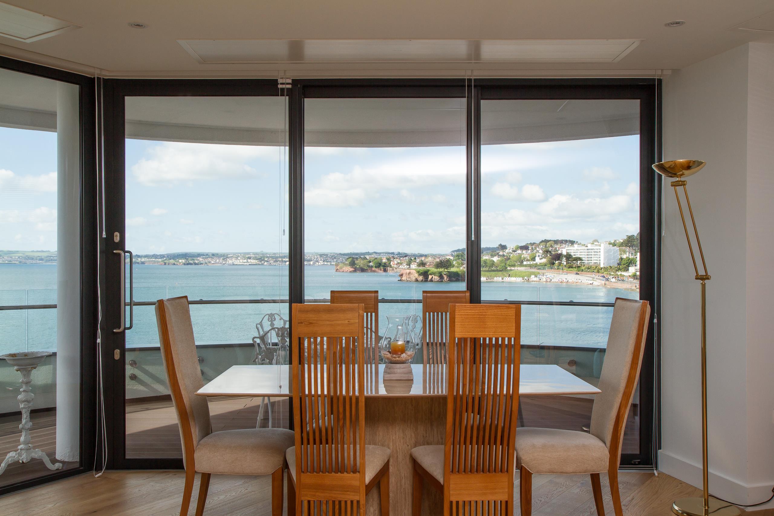 Interior dining room with Smart Systems Visoglide Plus sliding doors open to a sea-view terrace
