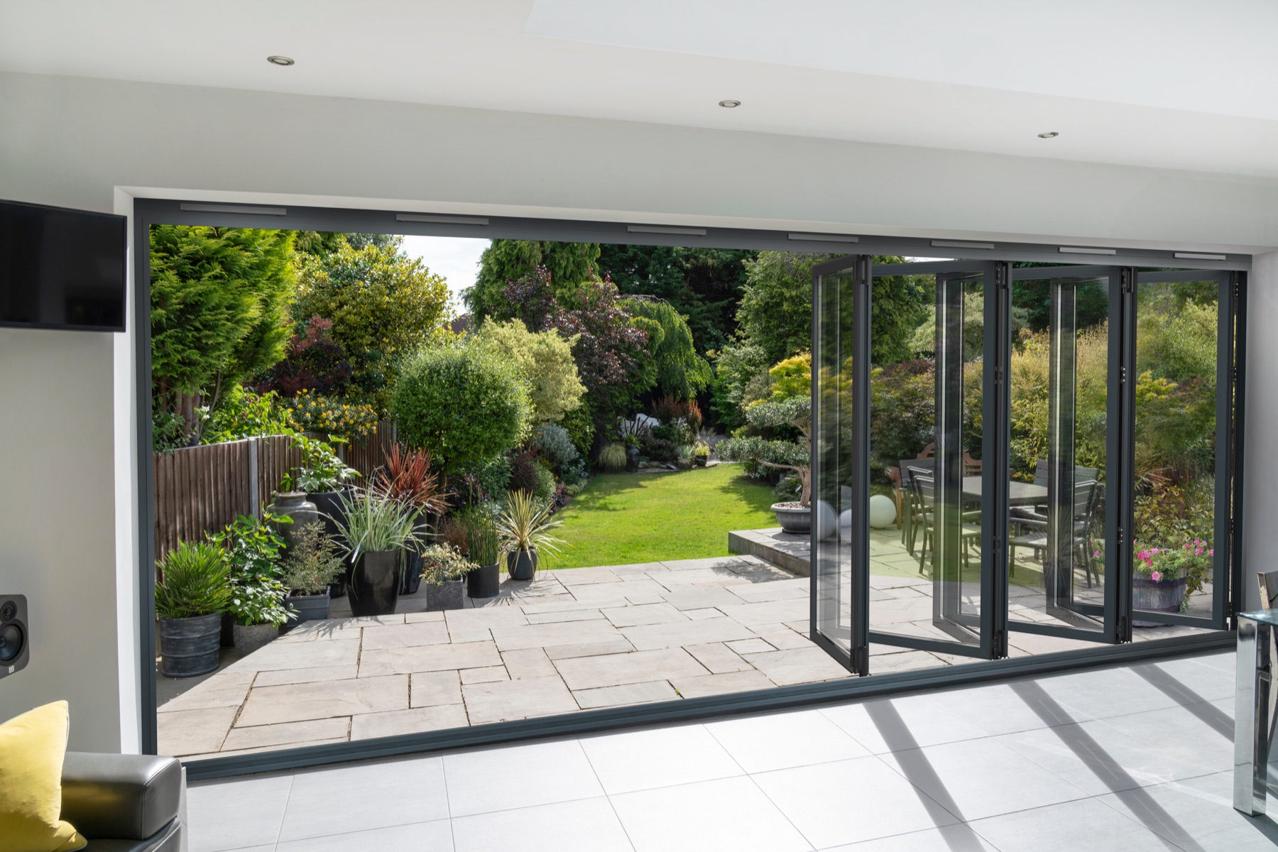 Anthracite grey Smart Systems Visofold 1000 bifold doors open onto a garden patio