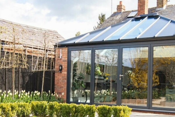 A brick-built home extension with a glazed hipped roof and bifold doors