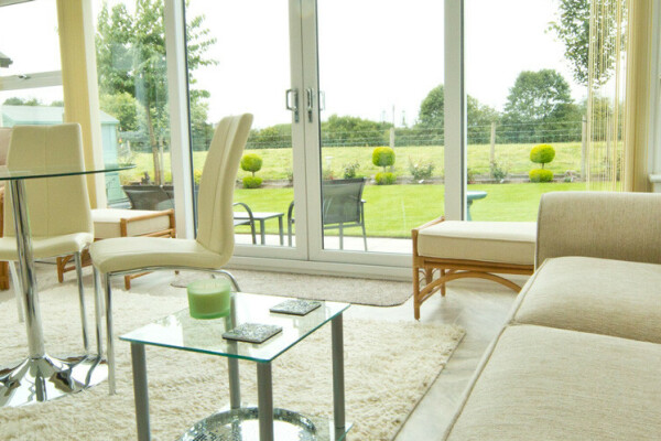Bright conservatory interior with a Livinroof hybrid roof, patio doors and garden view