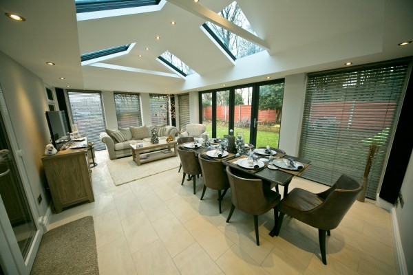 An anthracite grey orangery-style home extension with bifold doors, brick house and garden